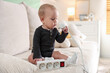 © New Africa - Child safety at home. Little girl playing with extension cord on sofa indoors