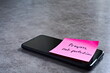© Shannon Muranyi - 'Progress, not perfection' sticky note left on smartphone. The bright note stands out against the keys, symbolising motivation, productivity, and a focused mindset.