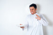 © rukuta.project - Muslim man refusing food while holding plate wearing white thobe isolated on white background. Rejection, dislike and refusal concept.