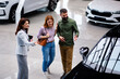 © djile - Couple inspecting new car with saleswoman in dealership