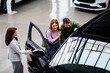© djile - Saleswoman showing car interior to couple in showroom
