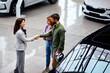 © djile - Saleswoman shaking hands with couple after car purchase