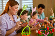 © djile - Mother painting easter egg with children at table