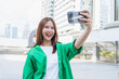 © sitthiphong - Happy young Asian woman traveler wearing green shirt with taking selfie photo on smartphone. summer tourism concept