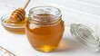© Yura - Honey Jar on Marble SurfaceGlass Jar Filled with Golden Honey on Light BackgroundUnlabeled Honey Jar in Natural Soft Light