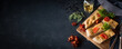 © gudrun - Freshly baked Italian focaccia bread pieces with tomatoes and fresh herbs on black countertop. Typical of mediterranean cuisine. Horizontal close-up from above with space for text.