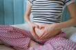 © wifesun - Pregnant woman creating a heart symbol with her hands on her growing baby bump, embodying the concepts of love, waiting for new life, care, and the precious bond of motherhood during pregnancy