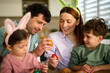 © djile - Parents and children holding painted easter eggs at home