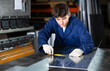 © JackF - Guy working at metallurgical plant measures sheet of iron using tape measure and marks the cutting line