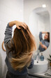 © Zoran Jesic - Young woman caring for long brown hair in bathroom