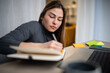© Zoran Jesic - Woman writing in notebook while working from home