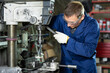 © JackF - Confident skilled operator in blue workwear and protective glasses, working on drilling machine in metalworking shop, performing holes in flat steel part