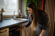 © Zoran Jesic - Woman operating built-in dishwasher in modern kitchen