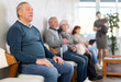 © JackF - Serious senior man calmly waiting in line at public healthcare facility before doctor consultation