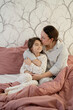 © ADDICTIVE STOCK - Mother kissing daughter in bed at home