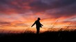 © Yuliia - Woman silhouette standing in tall grass field against dramatic sunset sky with orange and purple clouds creating peaceful moment of freedom and contemplation.