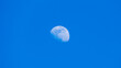 © cb.outside - Detailed daytime partial moon against bright blue cloudless sky