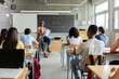 © Xavier Lorenzo - Young student group attending lesson with teacher in classroom. Diverse people learning during an academic lesson in a high school setting. Education and teaching concept.
