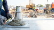 © CK Studio - Worker performing a concrete slump test with a measuring tape at a construction site for quality control and building material assessment.