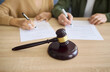 © Studio Romantic - Couple signing divorce document at court with gavel. Focus on legal paperwork and signature for separation agreement, showing mediation, law and asset split. Strong concept of legal conflict.