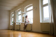 © Westend61 - Mature woman in empty room holding tablet looking out of window