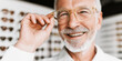 © Bonsales - Senior man smiling while trying new prescription eyeglasses at an optical clinic, pleased with clear vision and fit