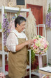 © Ekkasit A Siam - Senior asian female florist adjusting bouquet flowers with hand carefully in floral studio arranging product before photographing for online shop creative home business in retirement age