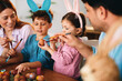 © djile - Family painting easter eggs together celebrating springtime holiday