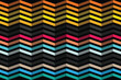 © Abid - A colorful abstract geometric pattern of chevron shapes in various vibrant hues and black accents