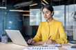 © Tetiana - An Indian businesswoman sits at a desk in an office, working with documents and a laptop