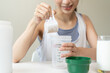 © Pormezz - Young sporty woman pouring protein powder into a cup to make replacement food meal after workout