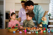 © djile - Parents and children decorating easter eggs at home