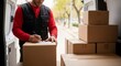 © Iqbal - Delivery man labeling packages in van for efficient shipping process