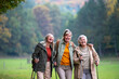 © Halfpoint - Active senior women hiking with trekking poles and dog in nature.