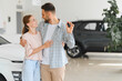 © Serhii - Happy couple holding new car keys in showroom