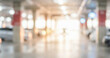 © al-sultan - Blurred view of an indoor parking garage with bright lights and white vehicles visible in the background. The overall atmosphere is spacious and modern.