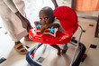© Alvaro Lavin/Stocksy - African infant boy learning walking in red baby walker