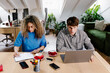 © Adrian Rodd/Stocksy - Pair of young adults collaborating on laptops at a common workspace