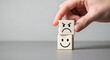 © Naz Piczz - Hand holding two cubes with contrasting facial expressions, happy and angry emotion feeling