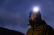 © Raymond Forbes LLC/Stocksy - Portrait of hiker with headlamp in dark look away
