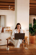 © Artem Podrez/Stocksy - Business woman working on laptop in contemporary hotel lobby