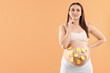 © New Africa - Thoughtful pregnant woman with notes with different names on her belly against orange background, space for text