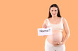© New Africa - Pregnant woman holding card with word Name and question mark on orange background, space for text