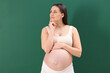 © New Africa - Choosing name for baby. Thoughtful pregnant woman on green background