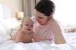 © New Africa - Mother and her cute baby on bed at home