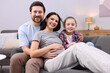 © New Africa - Pregnant woman, her husband and daughter on sofa at home