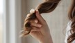 © antuanetto - Close-up of a young girl twisting her healthy brown hair around a finger, highlighting natural beauty and self-care concept
