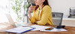© David - Portrait of successful bearded woman in holding cup of coffee and working with laptop while sitting at her working place
