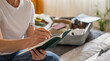 © Nanci - Person writing a packing checklist in a planner, preparing a suitcase for an upcoming holiday getaway, marking items and documents for a solo travel adventure and trip logistics
