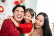 © Kawee - Asian young child hugging her parents during Lunar New Year celebration.
